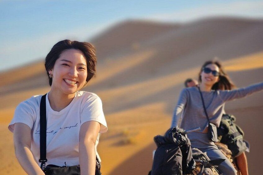 Due persone cavalcano cammelli in un paesaggio desertico con dune di sabbia. 4