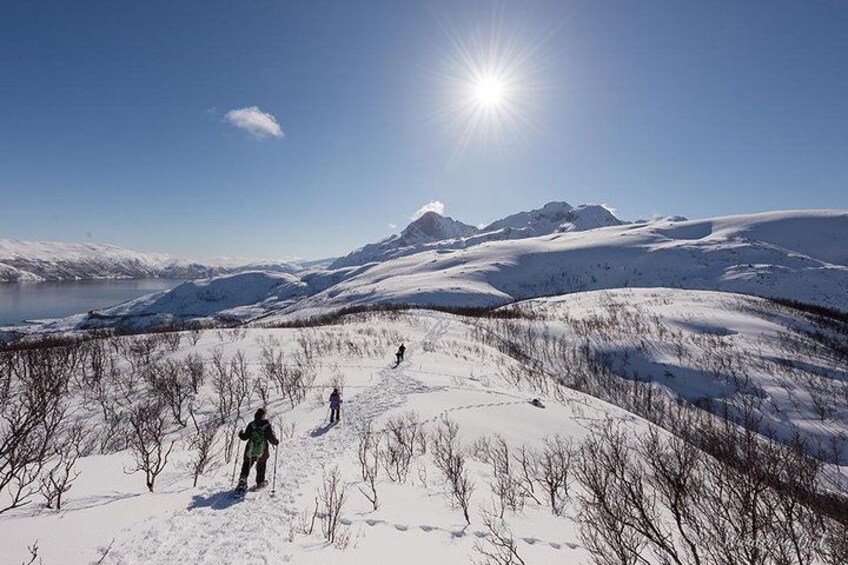 Un paysage enneigé avec un lac, des montagnes et des personnes qui font de la randonnée. 2