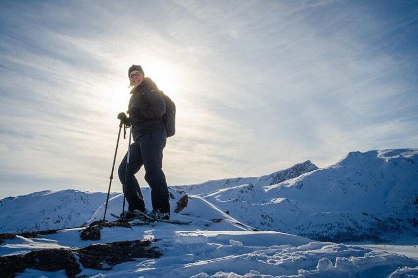 En person står på ski i et sneklædt bjerg under en klar himmel. 2