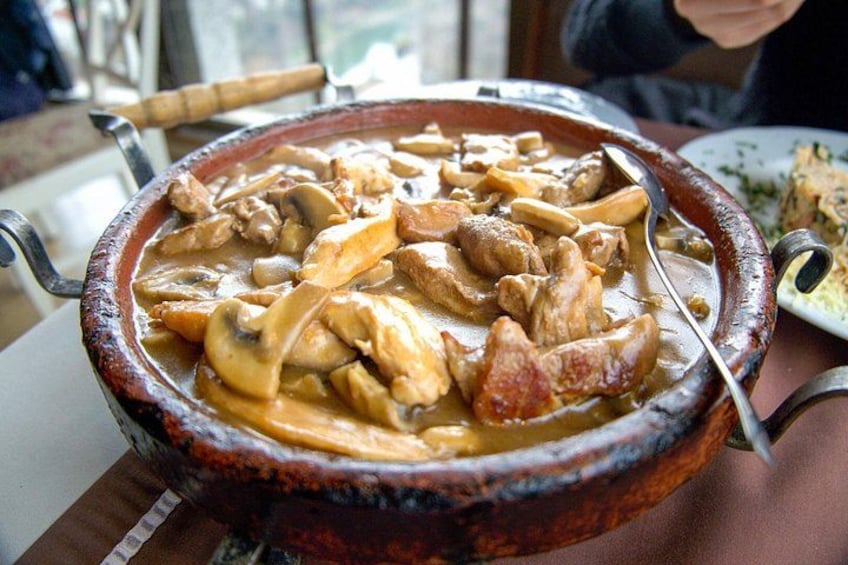 Una olla de cerámica grande llena de guiso, colocada sobre una mesa. 5