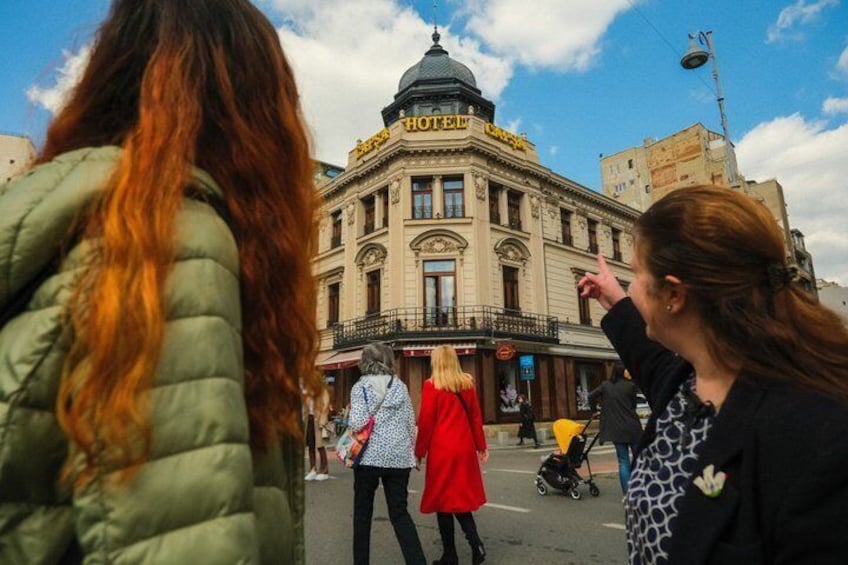 A historic building with a dome and balconies, a street with pedestrians, and a clear sky. 4
