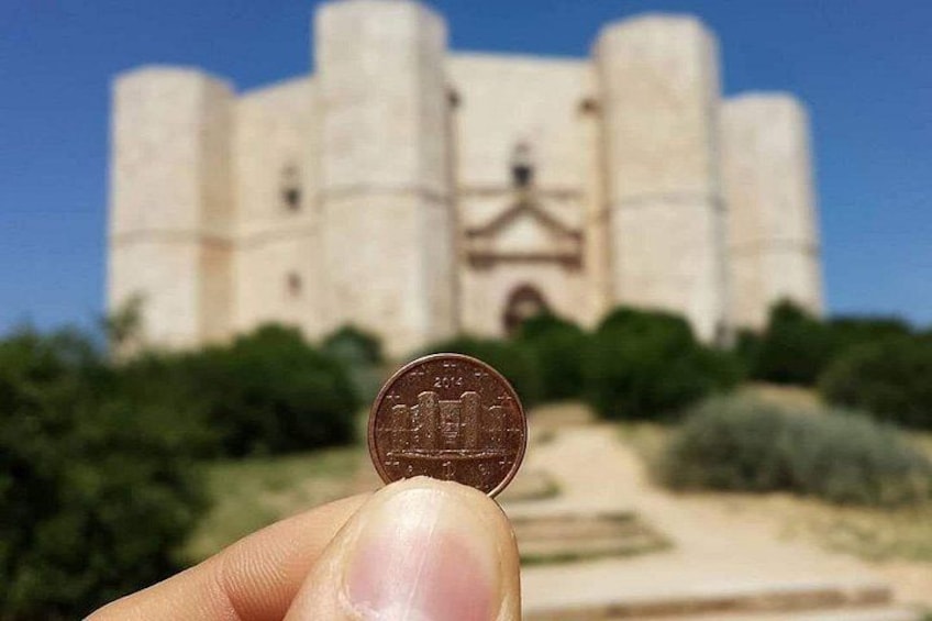 A hand holding a coin in front of a castle. 5