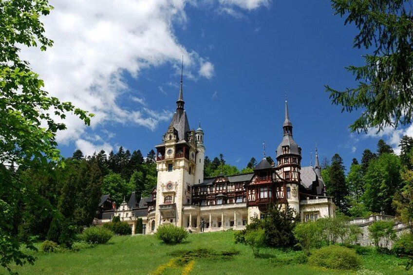A historic castle with two towers, surrounded by lush greenery and a clear sky. 2