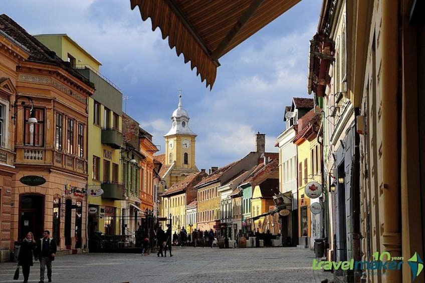 A historic square with colorful buildings, a prominent clock tower, and cobblestone streets. 3