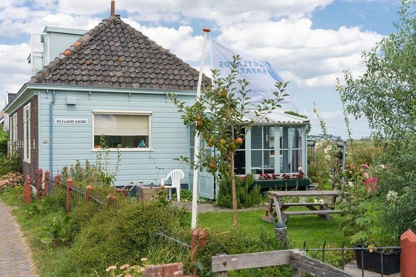 Una casa blu con un giardino e una piccola sedia bianca, con l'indicazione 'WETLANDS SAFARI'. 3