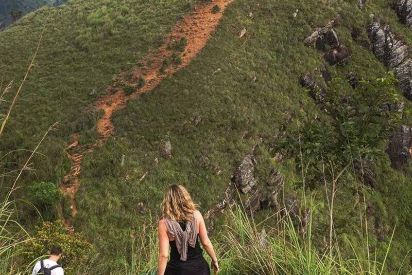 Eine Person geht auf einem Feldweg in einer hügeligen, grasbewachsenen Landschaft. 2