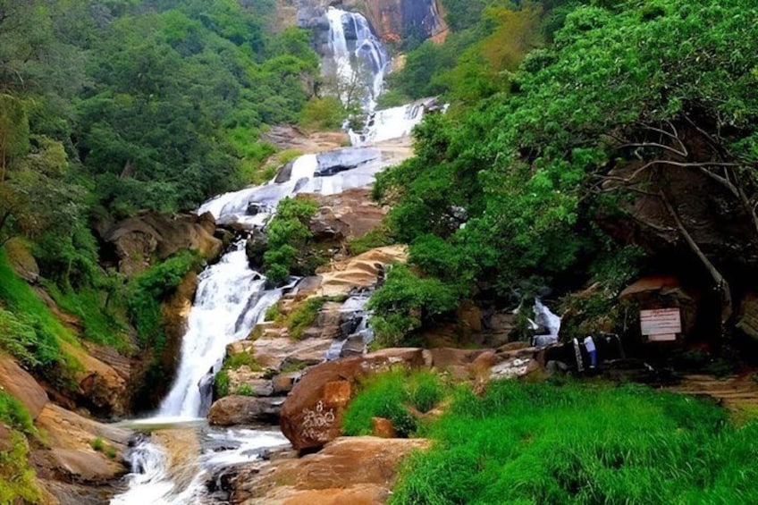 Ein mehrstufiger Wasserfall, umgeben von üppiger Vegetation und felsigem Gelände. 5