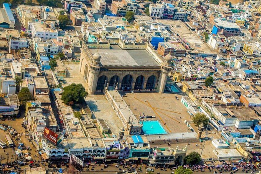 A densely packed urban area with a prominent historical building featuring arches and a dome. 2