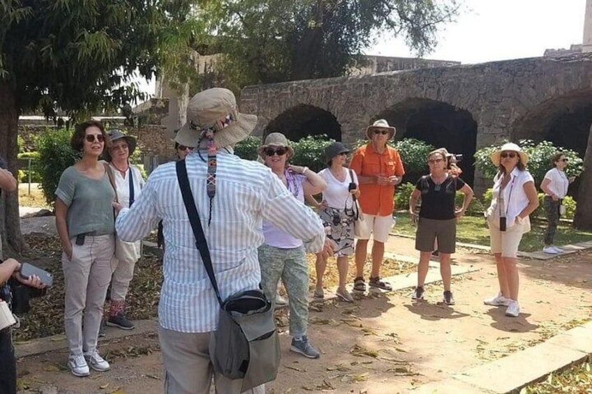 Eine Gruppe von Menschen steht vor einer historischen Stätte mit Steingewölben im Hintergrund. 2