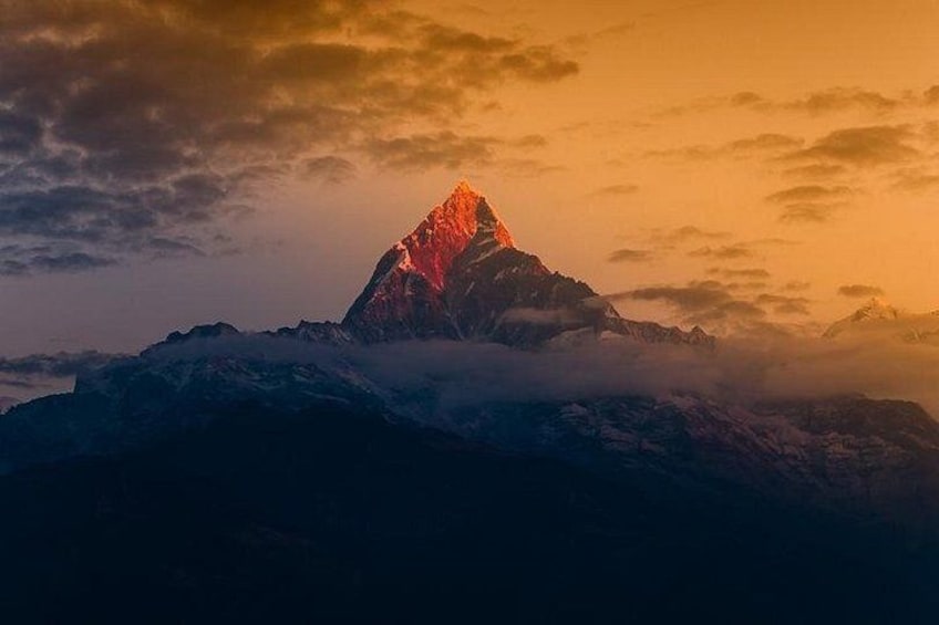 A mountain peak with a red glow, surrounded by snow-covered terrain and clouds. 1