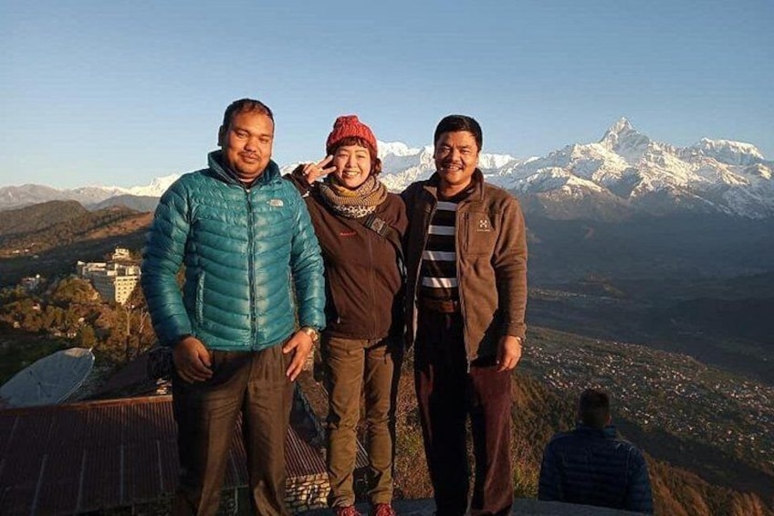 Three people standing on a mountain with snow-capped peaks in the background. 5