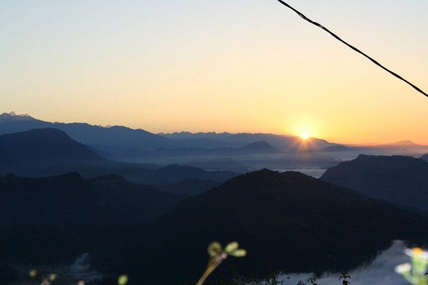 A mountain range at sunrise with the sun visible between the peaks. 2