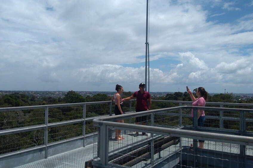 A group of people on a metal observation deck overlooking a cityscape. 3