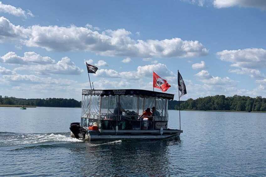 A boat with flags on a calm lake with a forested shoreline. 2