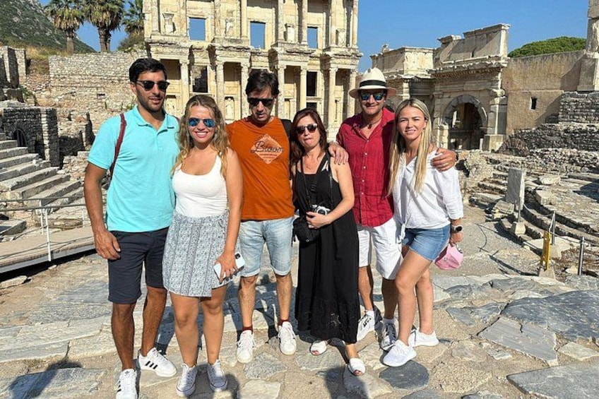 A group of people standing in front of ancient ruins with steps leading up to a large building. 2