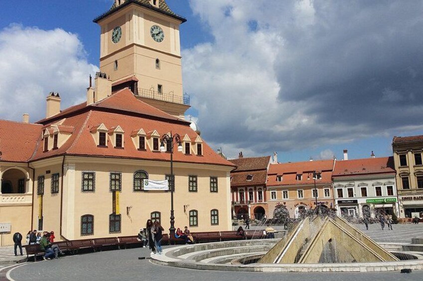 Ein historisches Gebäude mit einem Glockenturm, einem Brunnen und einer Menschenmenge. 4