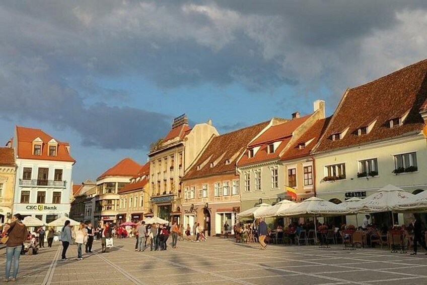 Ein belebter Platz mit historischen Gebäuden, Straßencafés und einer Bank. 5