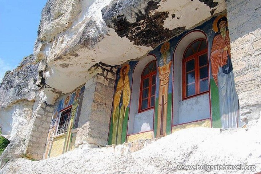 Una iglesia excavada en la roca con frescos coloridos y ventanas de arco. 1