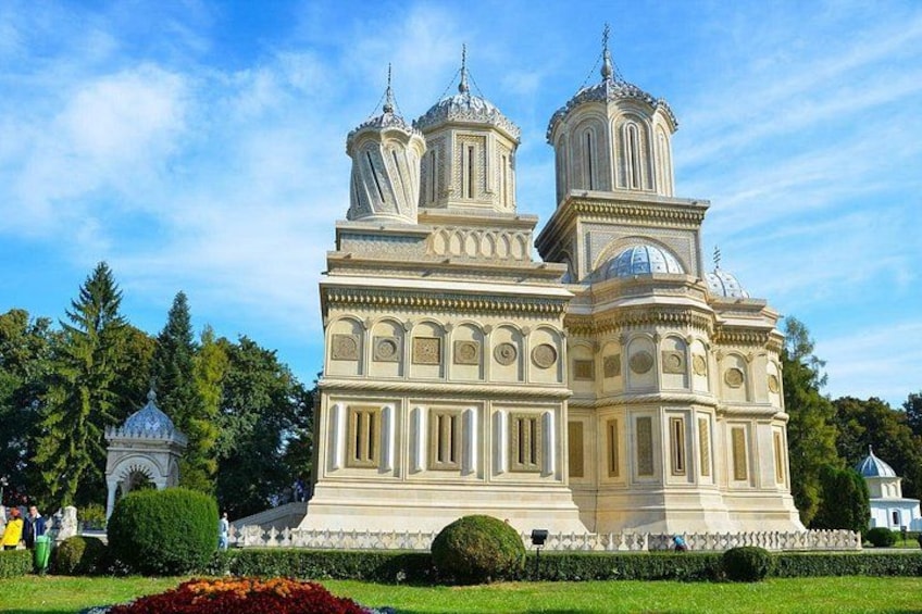 A large, ornate building with multiple domes and towers, surrounded by well-maintained gardens and trees. 5