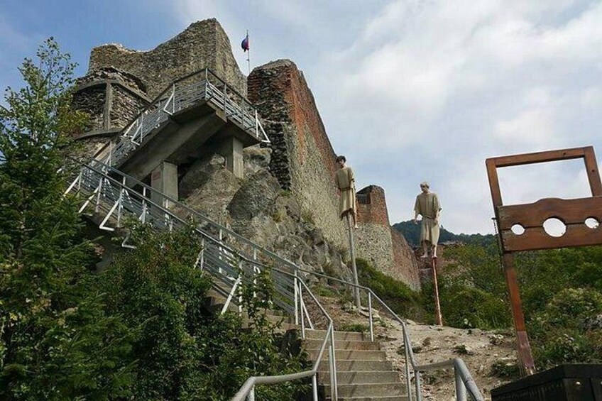 A historical stone structure with a staircase leading up to it, surrounded by greenery. 4