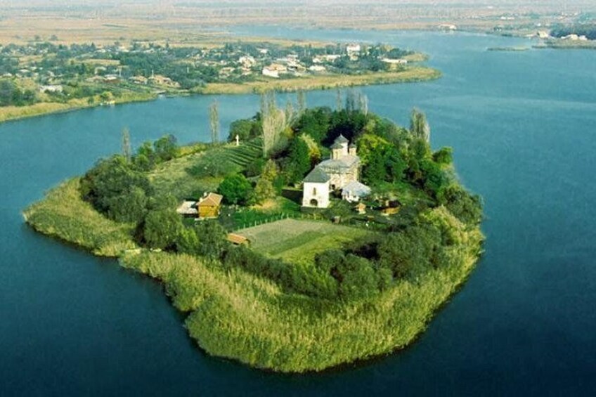 An island with a church, a small house, and a field. 3