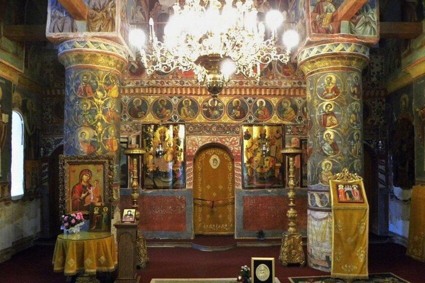 An ornate church interior with religious icons, a chandelier, and a golden door. 2