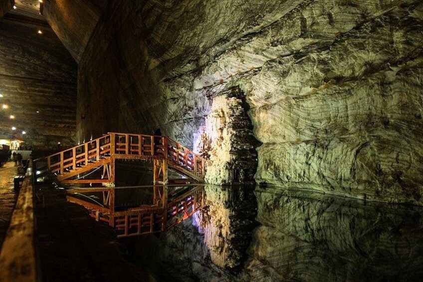 Une grotte dotée d’une passerelle en bois et dont la surface de l’eau reflète la lumière. 2