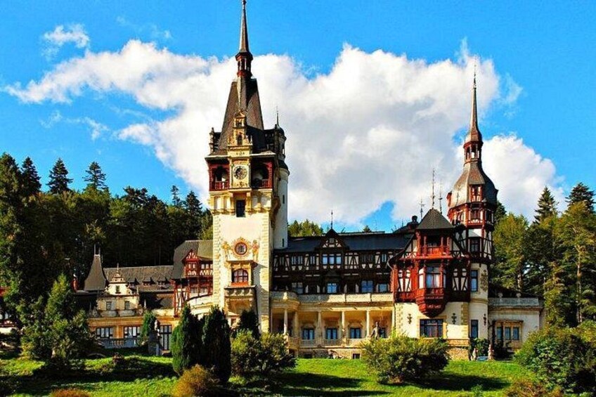 A historic building with two prominent towers, surrounded by lush greenery and a clear blue sky. 3