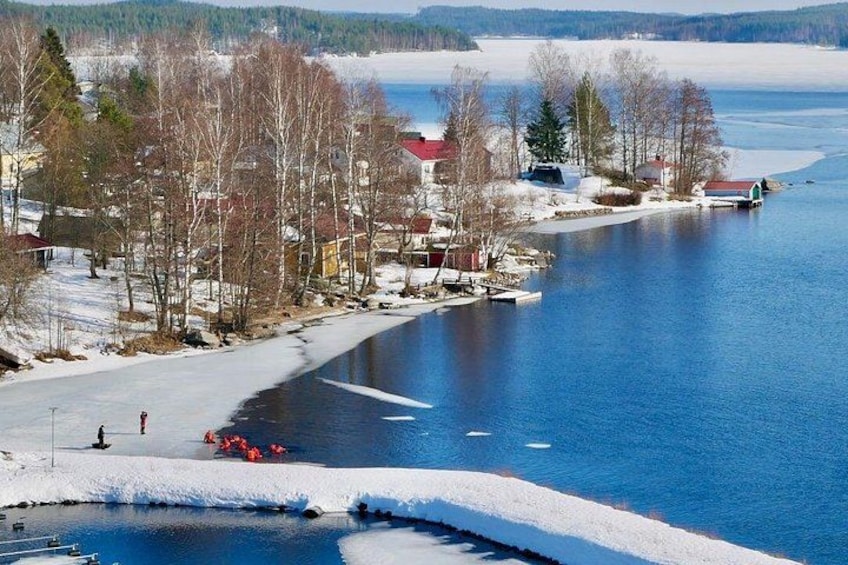 A frozen river with houses and trees along the banks, a dock, and a person walking. 4
