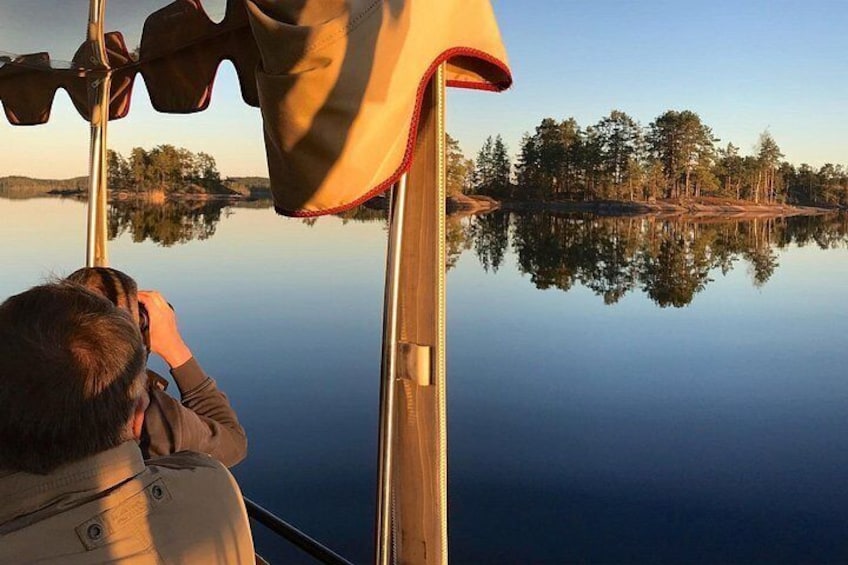 A person taking a photograph of a calm lake with trees reflected in the water. 2