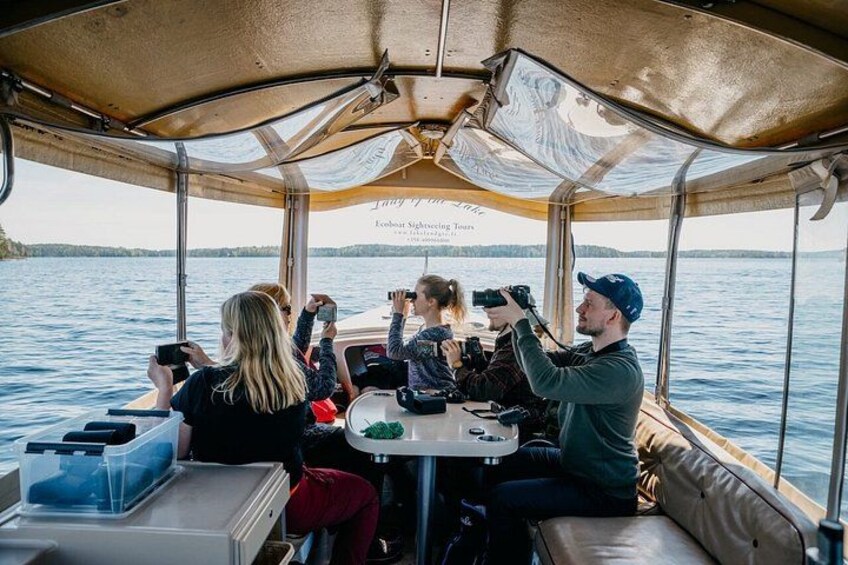 A boat with people taking photos, a table with items, and a view of water and land. 4