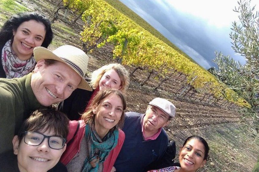 A group of people in a vineyard with rows of grapevines. 2