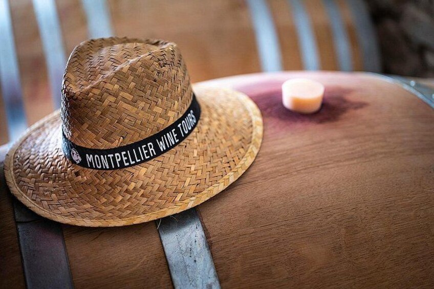 Un sombrero de paja con la inscripción 'MONTPELLIER WINE TOURS' en un barril de madera. 3