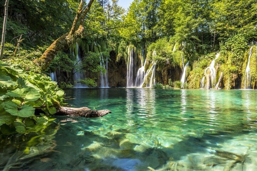 Un lago turquesa y cristalino rodeado de exuberante vegetación y múltiples cascadas. 5