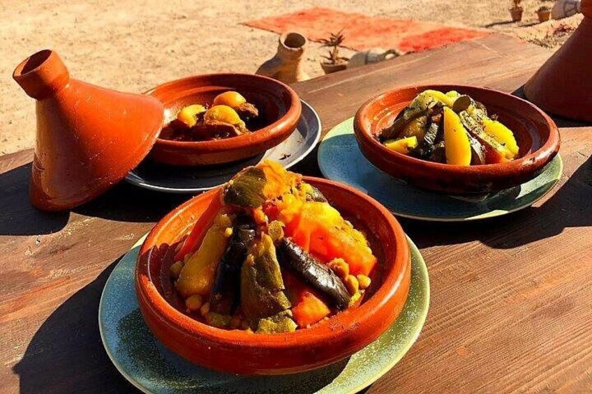 Three clay dishes with food on a wooden table. 4