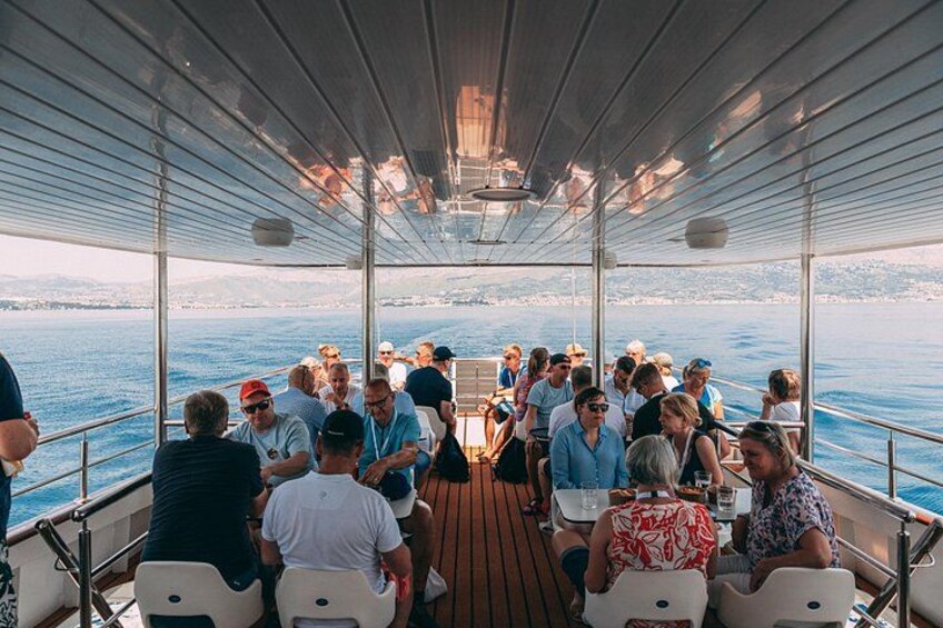 A group of people on a boat with a view of the water and distant land. 2