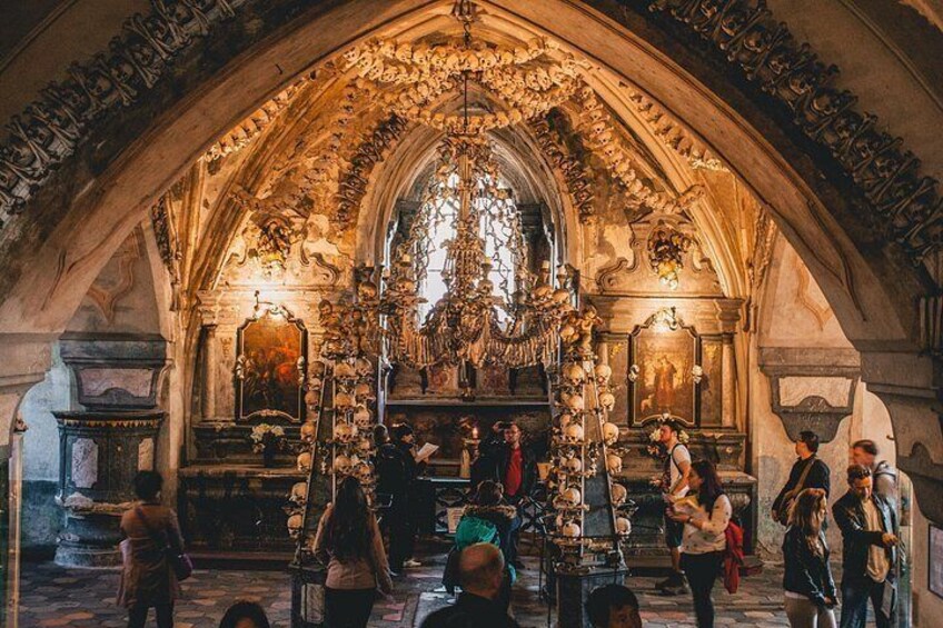 Interno di una chiesa ornata, con un soffitto ad arco alto, un altare centrale e un gruppo di persone riunite attorno. 3