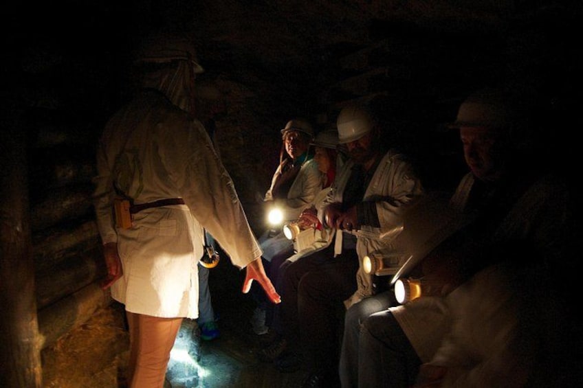 A group of people in a dimly lit cave with headlamps. 3