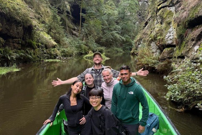 A group of people in a green boat on a river surrounded by lush greenery. 2