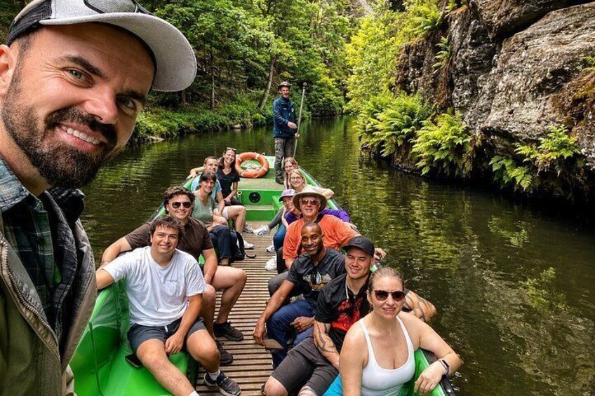 Un grupo de personas en un bote verde en un río estrecho rodeado de vegetación. 4