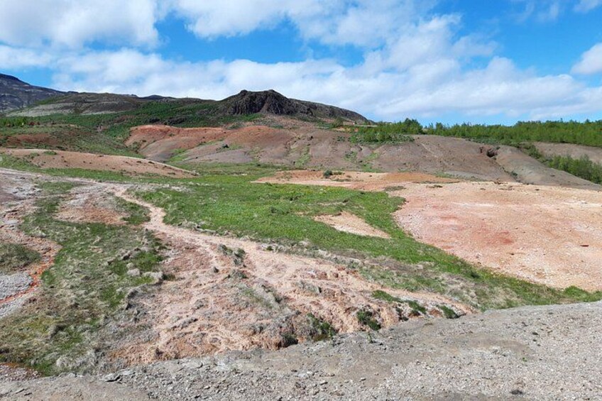 Un paysage accidenté, caractérisé par une colline imposante, un sentier de terre et une végétation clairsemée. 2