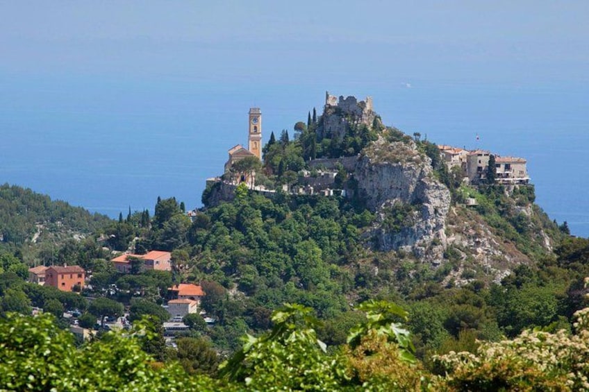 A coastal town with a prominent castle on a hill, surrounded by lush greenery and the sea. 3