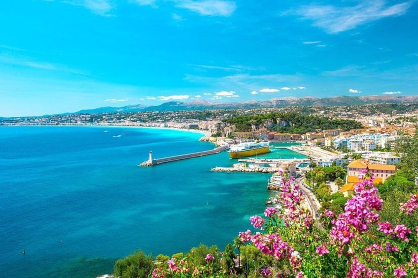 A coastal town with a clear blue sea, a pier, and buildings along the waterfront. 1