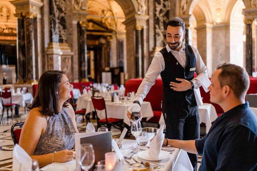 Un camarero sirviendo comida en un restaurante con arquitectura decorada. 3