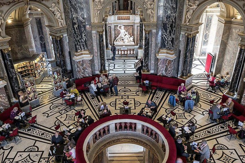 Un salón imponente con suelos de mármol, columnas ornamentadas y una estatua central. 2