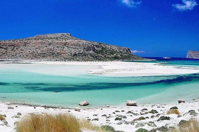 Ein Strand mit klarem türkisblauem Wasser, weißem Sand und Felsformationen. 1