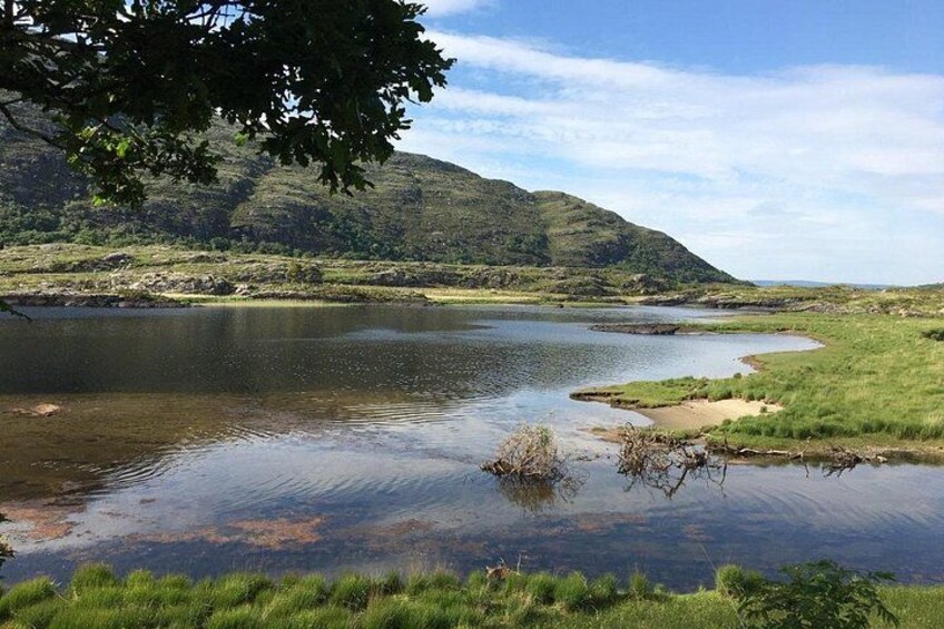 A calm river with grassy banks and a hill in the background. 2