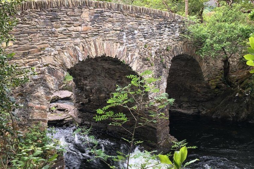 Un pont de pierre à arches enjambant une rivière aux eaux vives, le tout entouré d’une végétation luxuriante. 5
