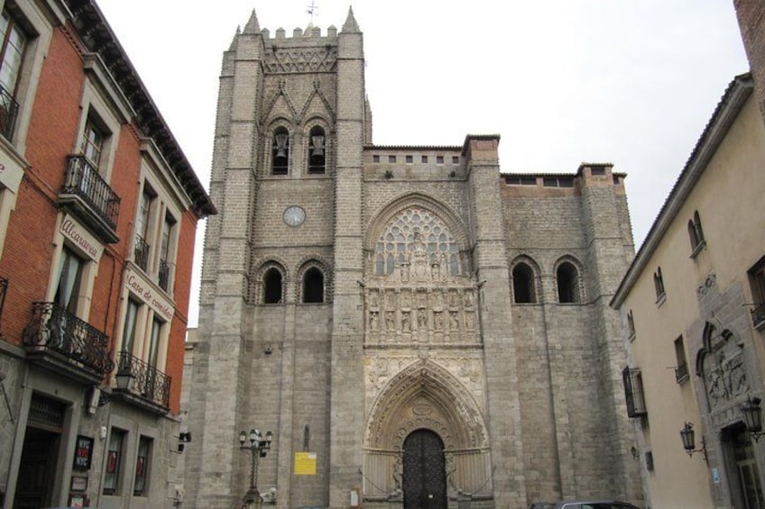 A historic stone church with a tall bell tower, arched windows, and a large central doorway. 2