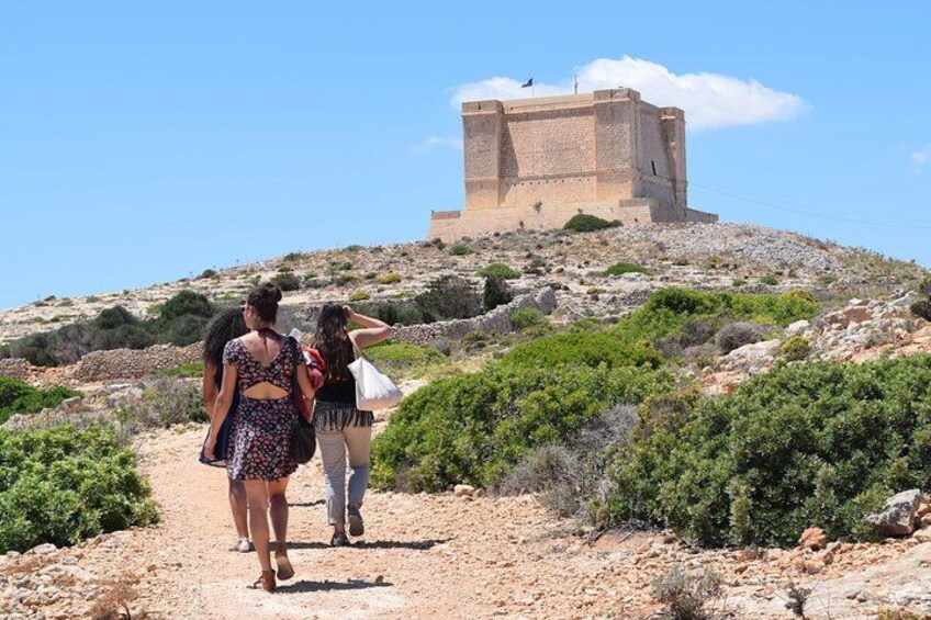 A group of people walking on a dirt path towards a stone fortress on a hill. 2